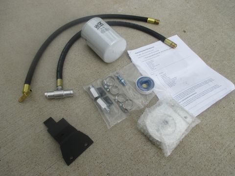 2007 Ford F-250 - A coolant filter kit is laid out on a concrete surface, including a WIX filter, hoses, fittings, and installation instructions.
