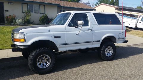 1992 Ford Bronco - This lifted 1992 Ford Bronco features a two-tone paint scheme with a black hood accent and aftermarket chrome wheels.