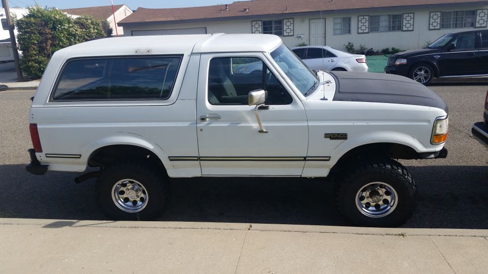 White 1992 Ford Bronco parked on street, aftermarket black hood