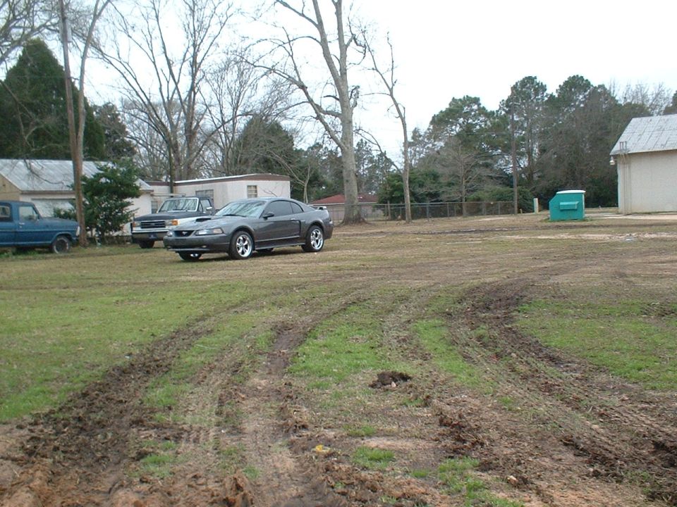 Gray 2003 Ford Mustang coupe parked in a muddy yard