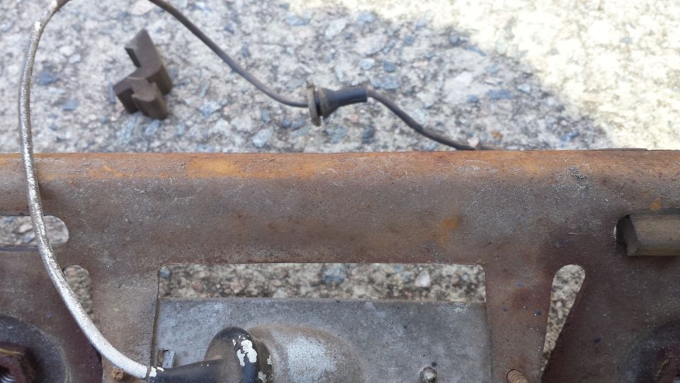 close-up of rusty metal part with wires and a black rubber grommet