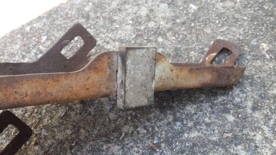 rusted metal bracket with square holes and a rectangular block