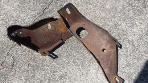 1976 Ford Ranchero - These two rusted metal brackets are shown resting on a concrete surface.