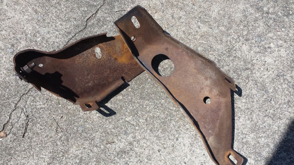 Two rusted metal brackets on concrete