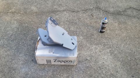 1976 Ford Ranchero - Automotive parts are placed on a cardboard box next to a can of spray paint on a concrete surface.