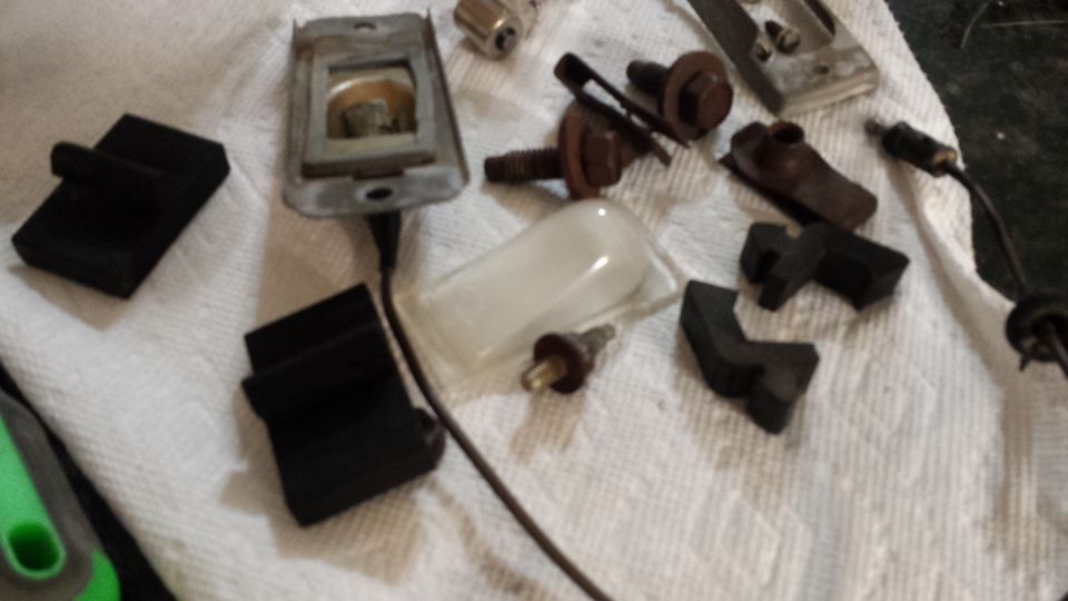 Collection of rubber bumpers, screws, and a light lens on a white cloth