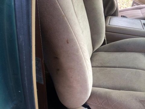 1990 Ford Bronco - Interior view of a car seat and console, showing fabric texture and some stains.