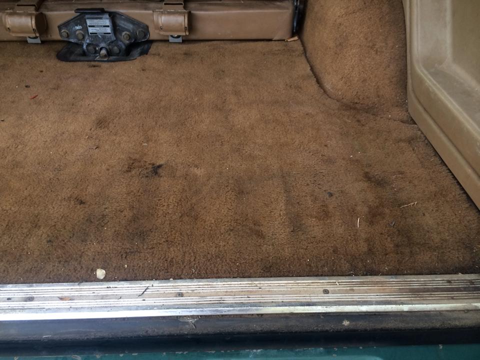 Interior cargo area carpet with some stains and a metal door sill