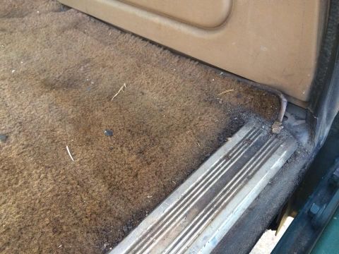 1990 Ford Bronco - Close-up view of the interior door sill and carpet, showing wear and tear.