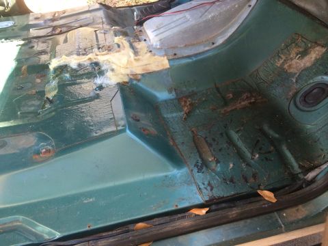 1990 Ford Bronco - The interior floor of the vehicle shows significant rust and damage to the insulation.