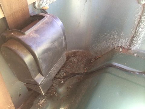 1990 Ford Bronco - Close-up of a seatbelt mechanism and the floor of a vehicle, showing signs of rust and wear.