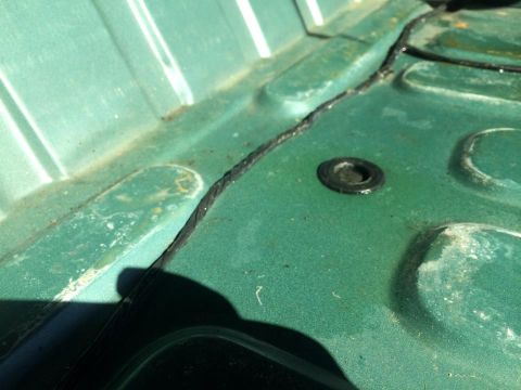 1990 Ford Bronco - Close-up of a vehicle's interior floor pan showing a grommet and seam detail.