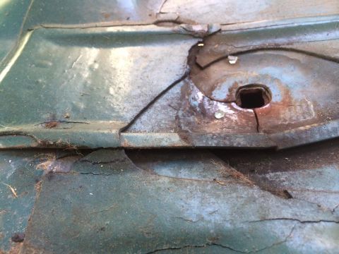 1990 Ford Bronco - This close-up shows significant rust and damage on a vehicle's metal panel, indicating a need for repair.