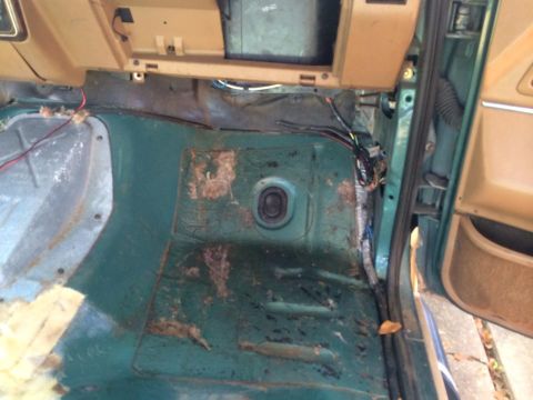 1990 Ford Bronco - The interior floor of a vehicle shows exposed wiring and signs of rust.