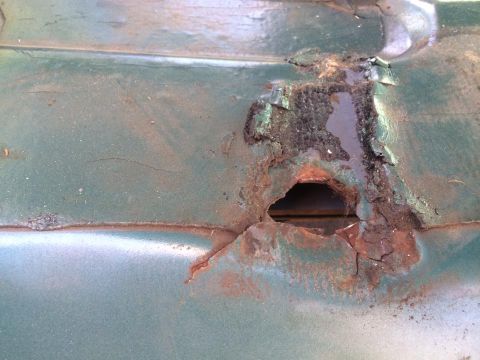 1990 Ford Bronco - Detail of significant rust damage on a green vehicle's exterior panel.