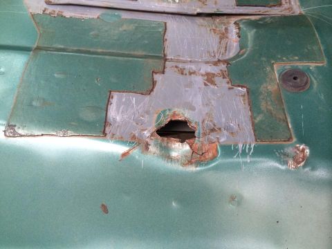 1990 Ford Bronco - Close-up of a corroded vehicle panel with patches and a large rust hole.