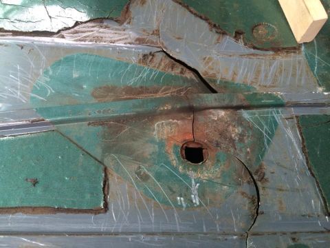 1990 Ford Bronco - Close-up of a damaged and rusted floor pan, showing significant corrosion and structural compromise.