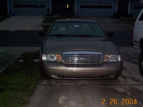 2003 Ford Crown Victoria - The front grille and headlights of a Ford Crown Victoria are visible in this nighttime photo.