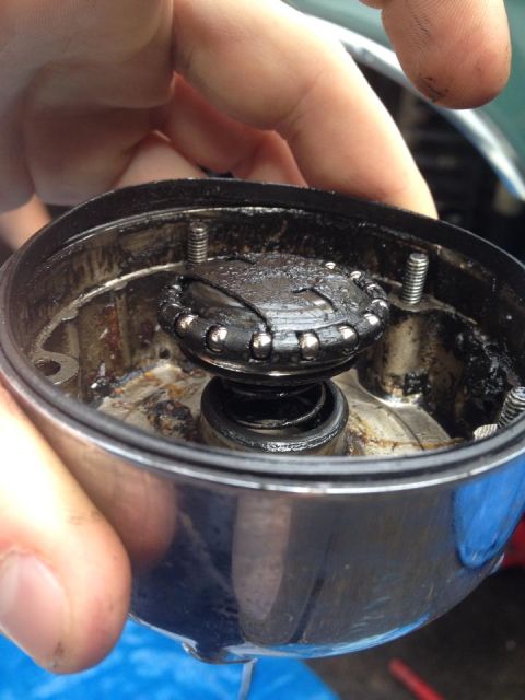 1990 Ford Bronco - A hand holds a greasy distributor cap, revealing its internal components like springs and ball bearings.