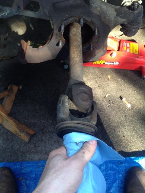 1990 Ford Bronco - Working on vehicle suspension and driveshaft components, with a red jack visible in the background.