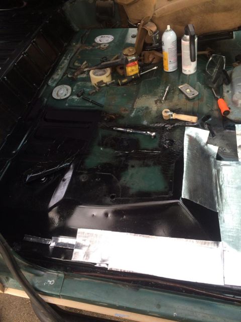 1990 Ford Bronco - The interior floor of a vehicle is shown with sound deadening material being applied and various tools scattered around.