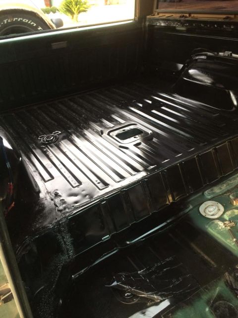 1990 Ford Bronco - The interior floor of a vehicle shows a ribbed metal surface with tie-down points and a central opening.