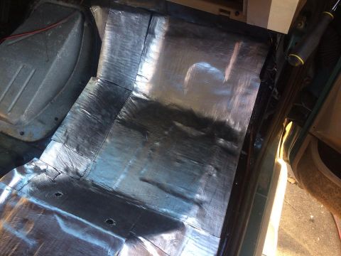 1990 Ford Bronco - Silver insulation being installed on the floor of a vehicle's interior.
