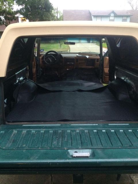 1990 Ford Bronco - The interior of an SUV is shown, with a focus on the dashboard and the rear cargo area covered in black carpeting.