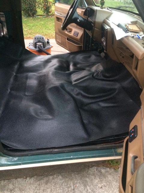 1990 Ford Bronco - New black floor liner installed in the interior of a 1990 Ford Bronco, with a shop vac visible.