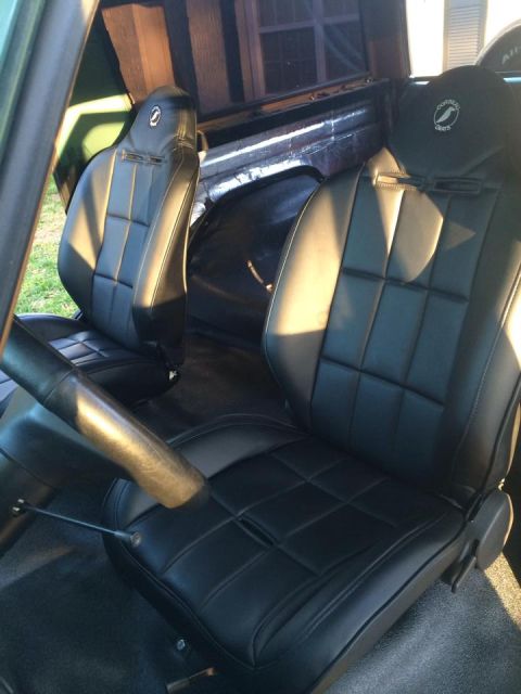 1990 Ford Bronco - The interior of a vehicle features new black leather seats with a quilted pattern and a roll bar.