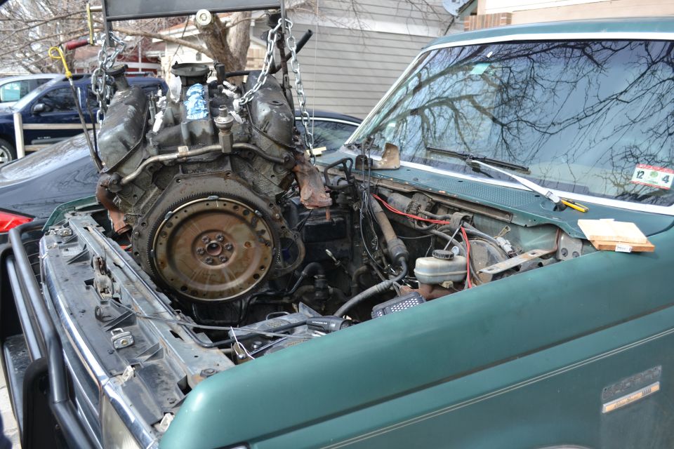 1990 Ford Bronco engine being lifted out by a hoist