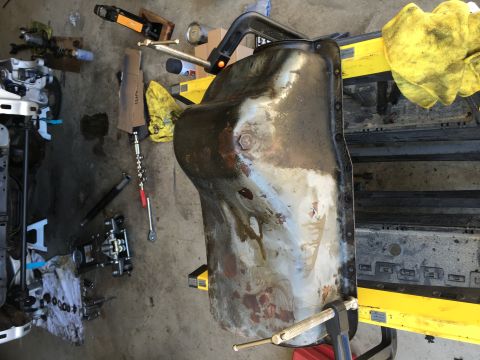 1987 Ford Bronco - An oil pan is clamped in a vise, surrounded by various tools and shop equipment.
