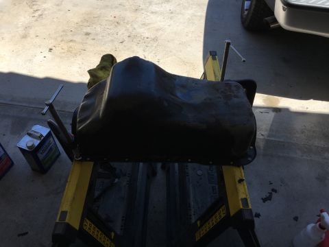1987 Ford Bronco - A black oil pan is shown on a stand, possibly during an engine rebuild. A can of oil is visible to the left.