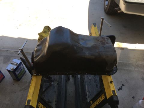 1987 Ford Bronco - Oil pan removed from a vehicle and placed on a stand for service.