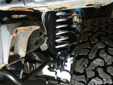 1987 Ford Bronco - Front suspension and tire detail of a truck, with SUPERMOTORS.NET branding visible.
