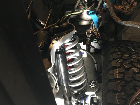 1987 Ford Bronco - The image shows a close-up view of a vehicle's suspension system and engine bay wiring, with a tire in the foreground.