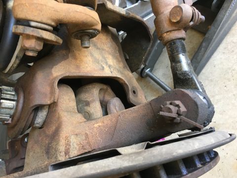 1987 Ford Bronco - Close-up view of heavily rusted vehicle suspension components, including tie rods and ball joints.