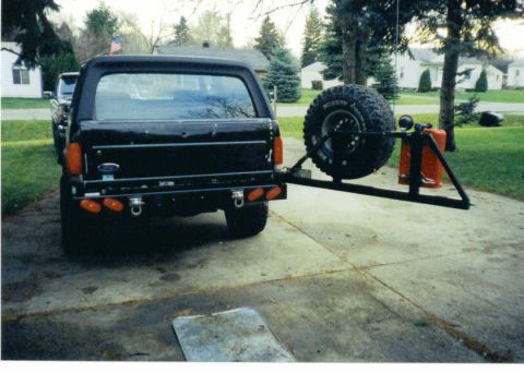1988 Ford Bronco - The rear of a black Ford Bronco is shown with a spare tire and gas can mounted on a custom carrier.
