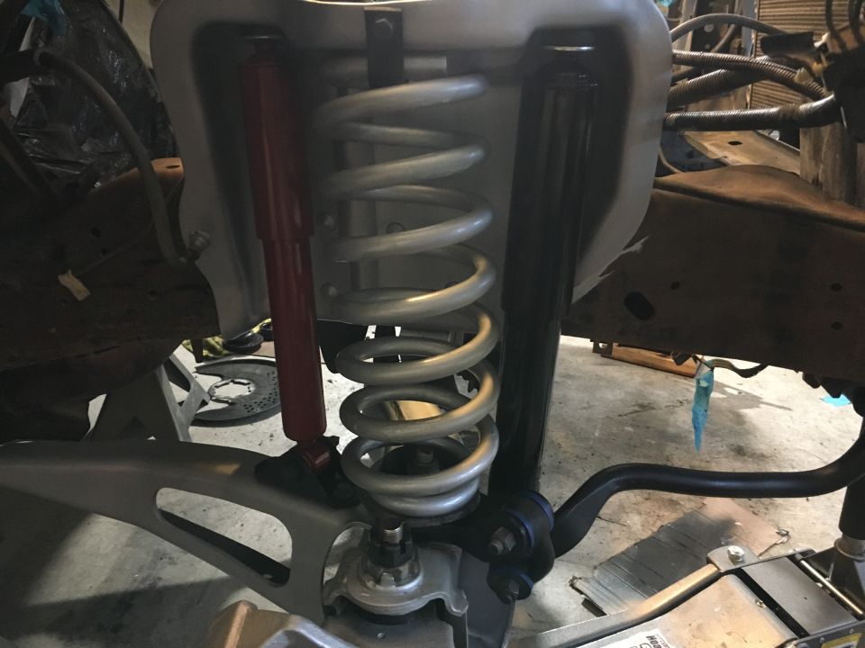 Front suspension assembly with silver coil springs and red/black shock absorbers