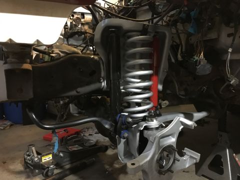 1987 Ford Bronco - Close-up of vehicle suspension and engine bay during a rebuild, showing various parts.