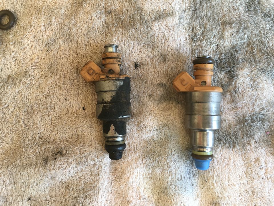 Two fuel injectors, one dirty and one clean, on a towel