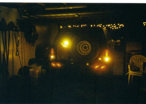 1988 Ford Bronco - Rear view of a dark Ford Bronco with its spare tire mounted, illuminated by interior and exterior lights.