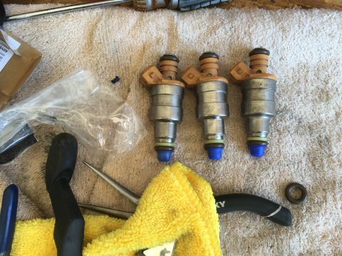 1987 Ford Bronco - Fuel injectors are laid out on a towel alongside various tools and a plastic bag.