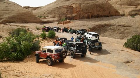 1979 Ford Bronco - A convoy of off-road vehicles navigates a sandy, rocky trail in a desert landscape.