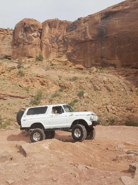 1979 Ford Bronco - A white 1978 Ford Bronco navigates a desert landscape, its lifted suspension ready for off-road adventure.