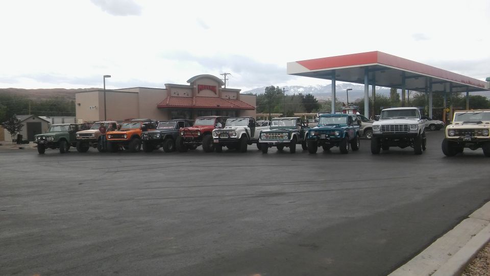 Several Ford Broncos and other SUVs parked in a line at a gas station