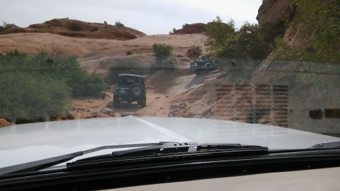 1979 Ford Bronco - Two vehicles navigate a challenging off-road trail with steep, rocky inclines and sparse vegetation.