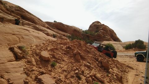 1979 Ford Bronco - Two off-road vehicles navigate a challenging desert landscape with red rock formations.