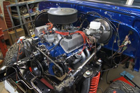 1979 Ford Bronco - The engine bay of a blue 1979 Ford Bronco is shown, its V8 engine and various components.