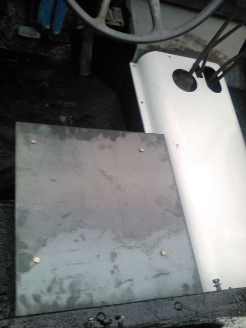 1991 Ford Bronco - Interior view of a vehicle, showing a metal floor panel and a white console with cables.
